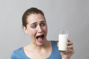 Žena koja sa strahom gleda u čašu mlijeka