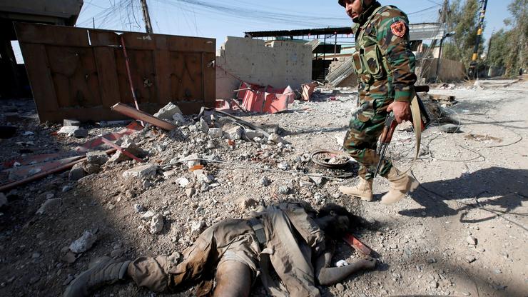 Pripadnik kurdske Peshmerge prolazi pored poginulog ISIL-ovca