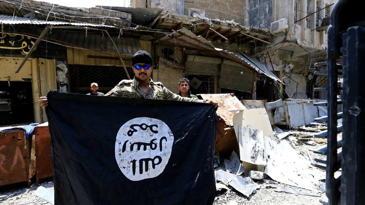 Pripadnik snaga iračke vojske drži u rukama zarobljenu zastavu ISIL-a